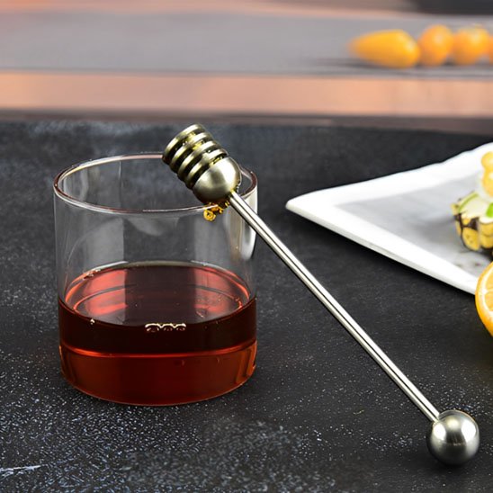 Cuillère à miel inxo appuyé sur verre