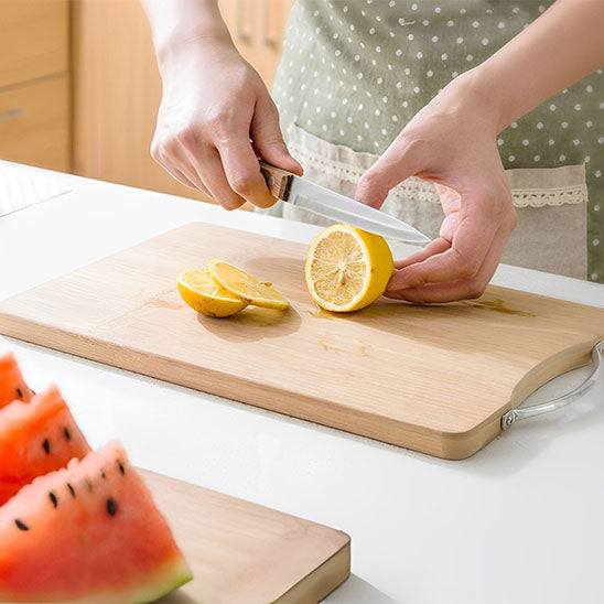 mains-coupent-citron-sur-planche-à-découper-bambou