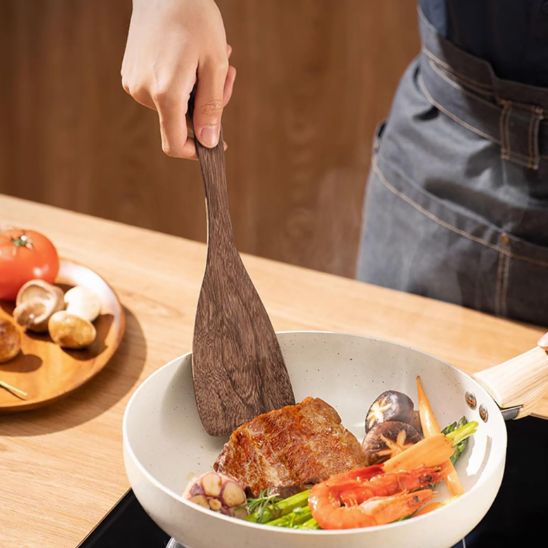 homme-retire -viande-de-la-poêle-avec-spatule-en-bois
