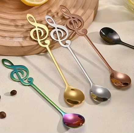 Cuillère à café en clé de sol de couleurs différentes accotées sur plateau de service bois