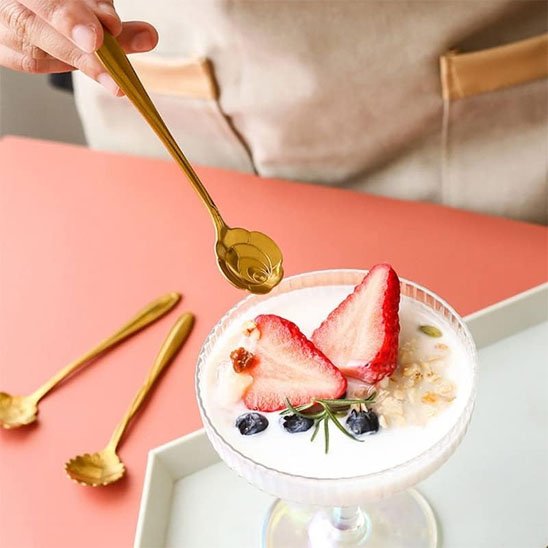 Cuisinier tient cuillère à café fleur vers dessert
