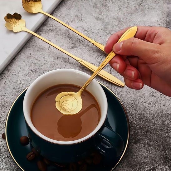 Femme tient cuillère forme rose au-dessus de tasse café noir