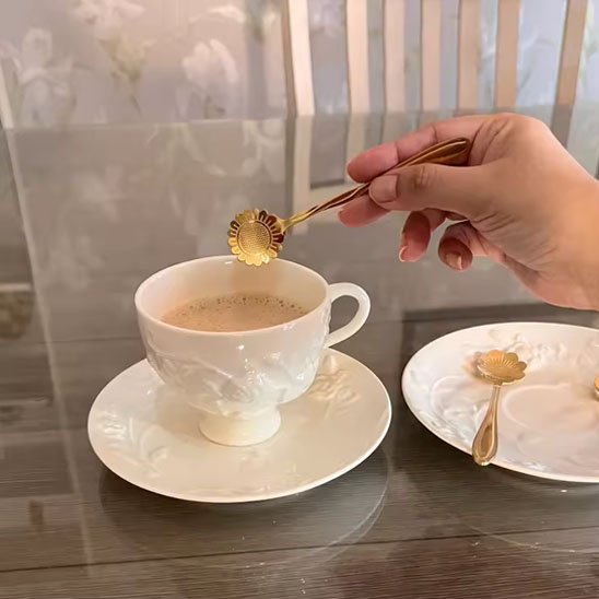 Femme tient cuillère en forme de tournesol au-dessus de tasse café au lait