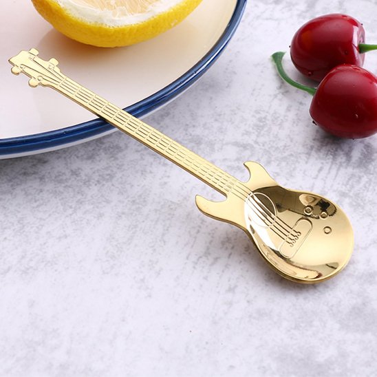 Cuillère à café guitare dorée accotée sur assiette