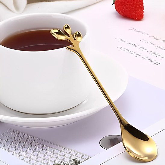 Cuillère à café motif feuille dorée appuyée sur une tasse