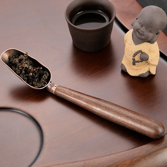 Cuillère à thé de fueilles de thé sur plat de service avec petit boudha