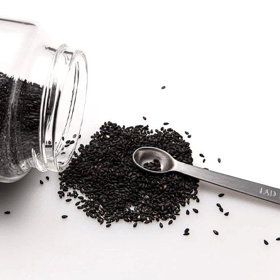 Bocal renversé sur contoir avec cuillère doseuse reposant sur graines éparpillées
