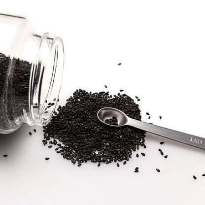 Bocal renversé sur contoir avec cuillère doseuse reposant sur graines éparpillées