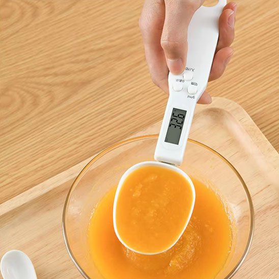 Cuillère doseuse​ suspendue au-dessus de bol de jaunes d'œufs