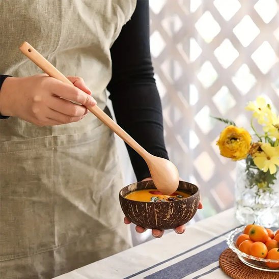 Cuisinier sert soupe avec cuillère en bois 