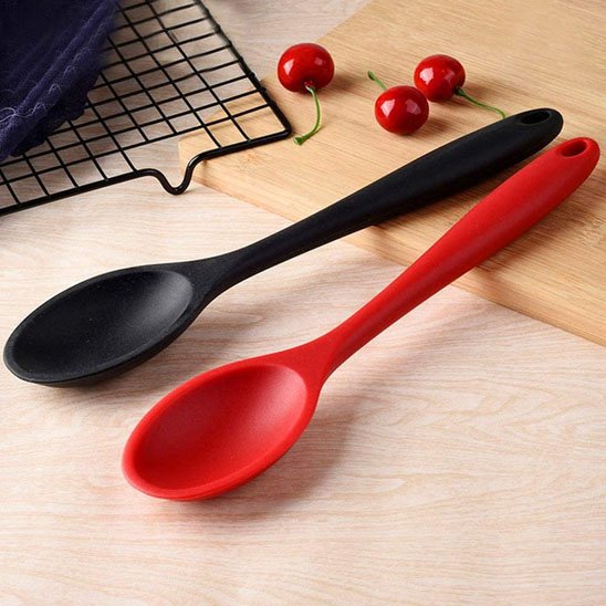Une cuillère en silicone noire et une rouge sur contoir cusine
