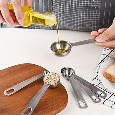 Cuisinier verse huile dans cuillères doseuses inox