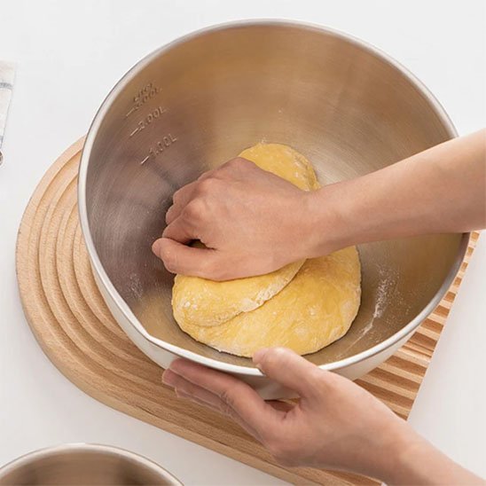 Cuisinère pétrit pâte dans cul de poule inox