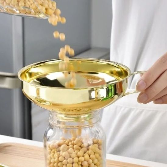 femme transvase haricots secs dans bocal utilisant entonnoir à confiture doré