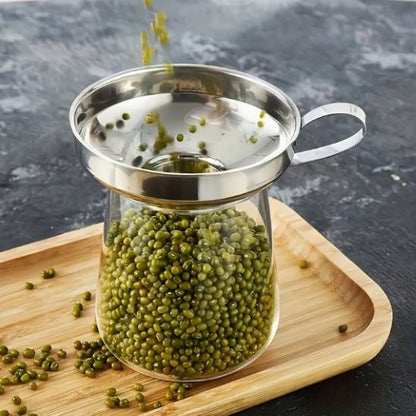 petits pois verts tombant dans un bocal à travers un entonnoir à confiture