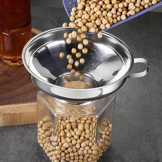 pois chiches secs versés dans un bocal à travers un entonnoir à confiture