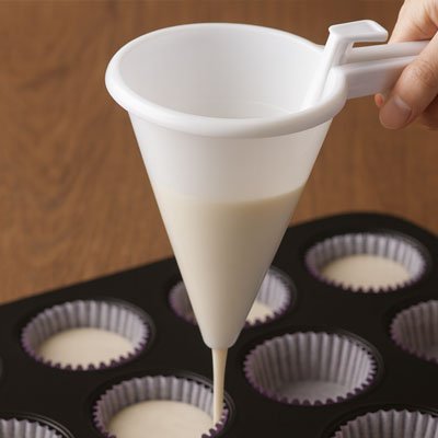 pâte versée dans caissettes à muffins blanches avec entonnoir à piston conique