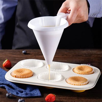 pâte versée dans caissettes à muffins blanches avec entonnoir à piston conique