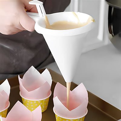 pâte versée dans caissettes à muffins roses avec entonnoir à piston conique