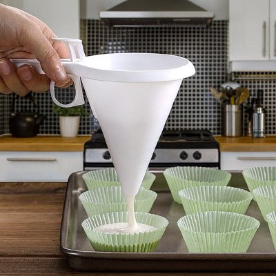 pâte versée dans caissettes à muffins vertes avec entonnoir à piston conique