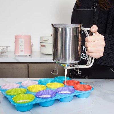 pâte versée dans moule à muffins multicolore avec entonnoir à piston inox
