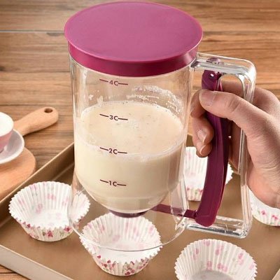 Entonnoir à piston transparent rempli de pâte tenu au-dessus de moules à muffins