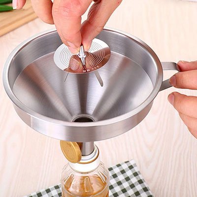 femme retire filtre amovible d'un entonnoir inox