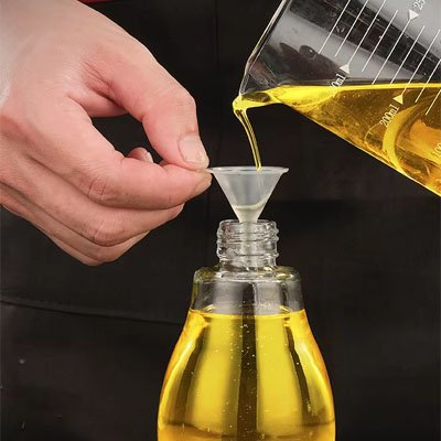 homme utilise entonnoir miniature pour verser huile dans bouteille à goulot étroit