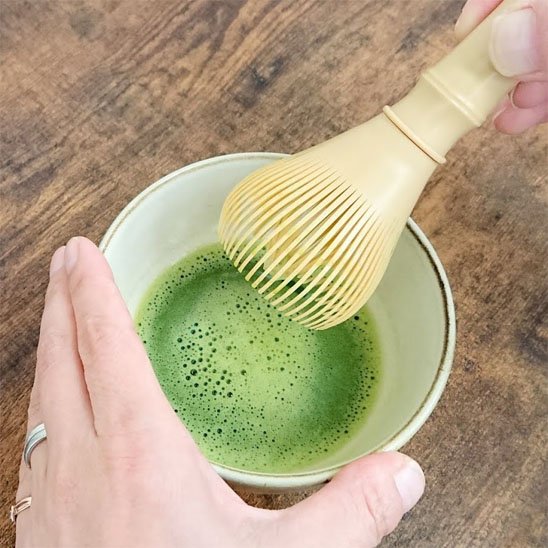 mains tiennent bol thé et fouet matcha