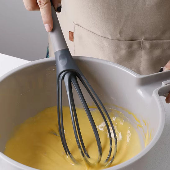 homme-mélange-oeufs-avec-fouet-ballon-gris