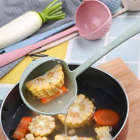 louche de maïs et bouillon au-dessus d'une casserole de soupe