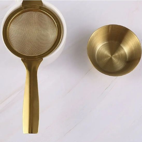 tamis doré sur tasse avec coupe à côté