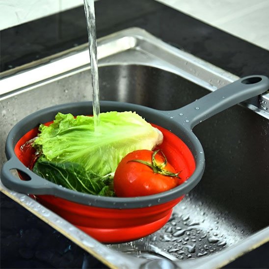 passoire pliable contenant légumes reposé sur évier 