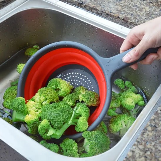 main tient passoire par poignée pour ramaser broccoli du fond d'évier