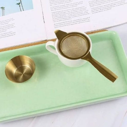 tamis or  sur plat vert dans tasse avec coupe à côté 