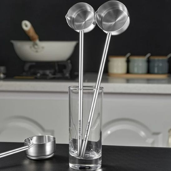 deux louches debout dans un verre et une  sur comptoir à côté