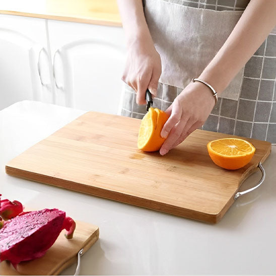femme-coupe-orange-sur-planche-à-découper-bambou