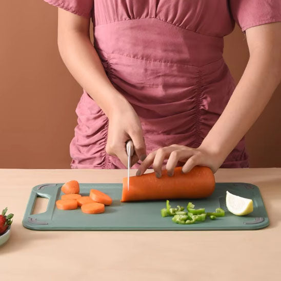 ffemme coupe carotte sur coté plastique de planche à découper à deux faces