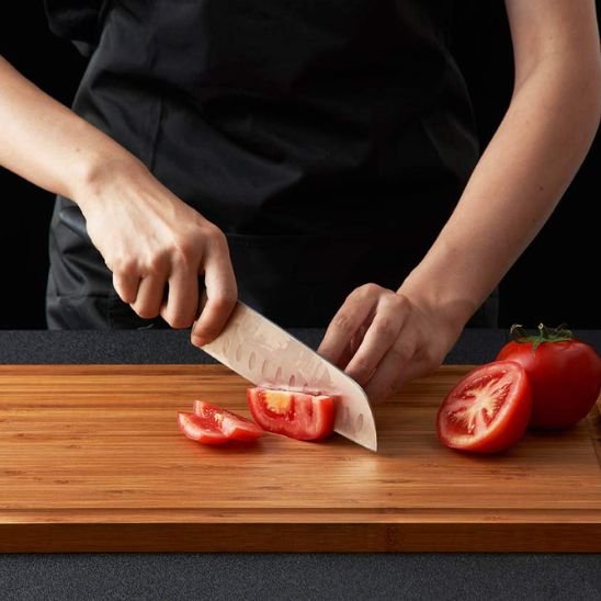 homme tranche tomate sur planche à découper en bois