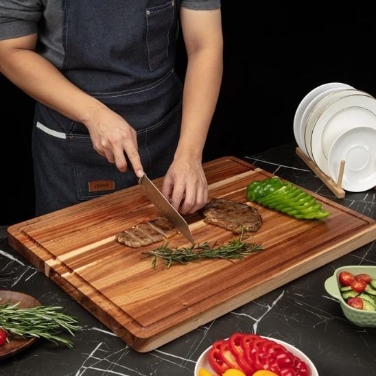 homme coupe steak sur planche à découper en bois