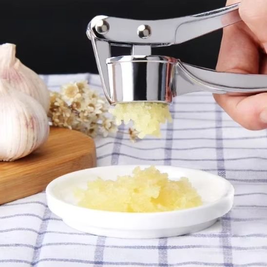 presse a ail écrassant ail dans petite assiette blanche