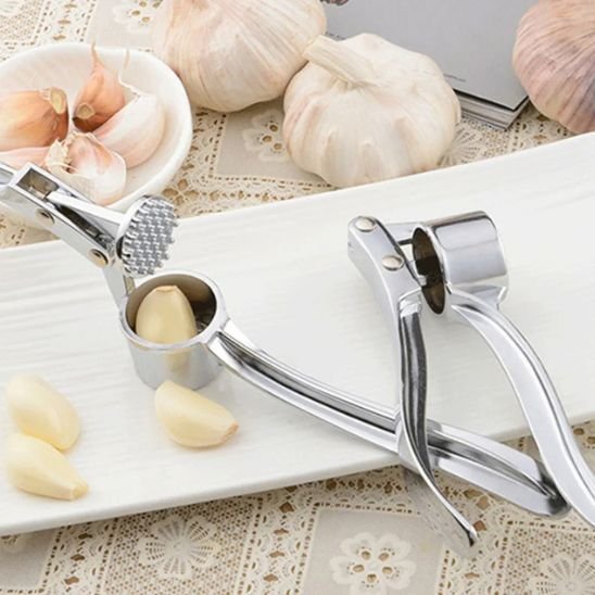 presse a ail avec ail dans compartiment sur assiette blanche entouré d'ail 