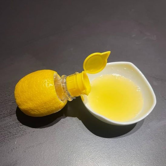 citron percé avec presse agrume accoté sur petit bol de jus