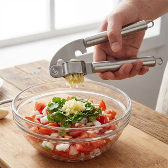 cuisiner utilise presse ail d'une main pour prépare salsa