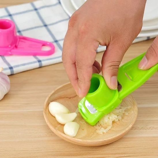 femme broie ail dans petit plat en bois  avec presse a ail manuel