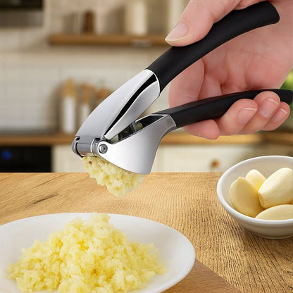 Main écrase ail dans assiette utilisant presse ail