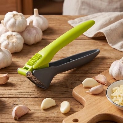 Presse ail sur comptoir cuisine bois entouré d'ail frais