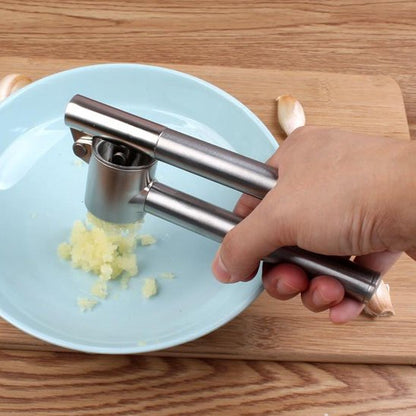 main écrase ail sur assiette bleue utilisant Presse ail 