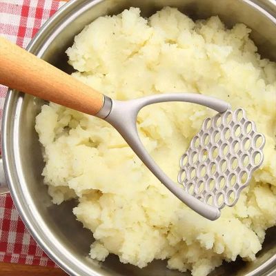 presse purée manuel au dessue d'eun marmite de pommes de terre pilées