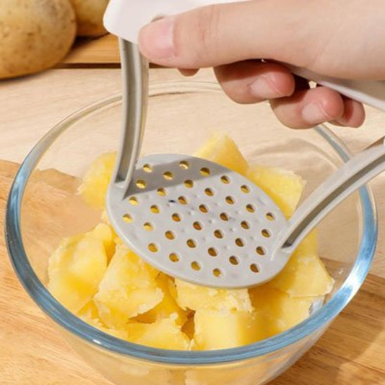 homme écrase des pommes de terre dans bol en verre avec presse purée